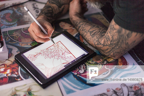 Tattooist sketching tattoo design on digital tablet