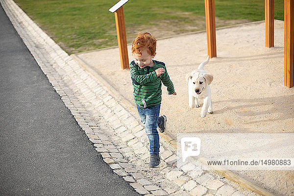 Boy running away from pet puppy