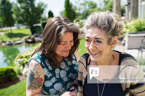 Frau lacht mit ihrer Mutter im Garten