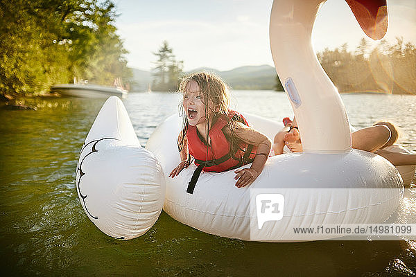 Mädchen spielen auf einem aufblasbaren Schwan im See