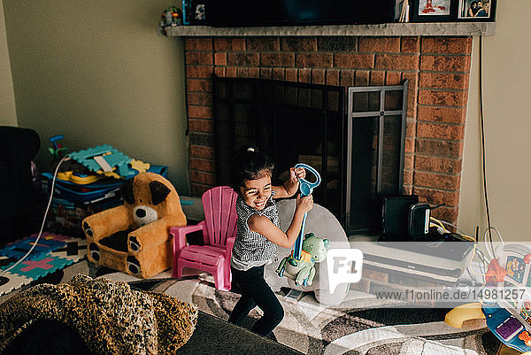 Mädchen lacht beim Spielen mit Spielzeug im Wohnzimmer