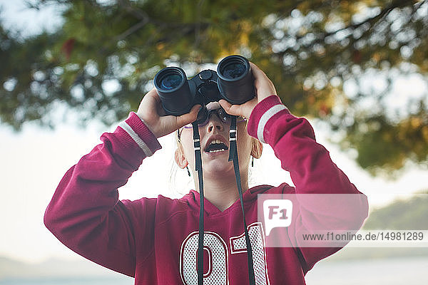 Girl looking up through binoculars