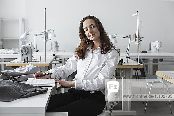 Modedesigner sitzt am Schreibtisch im Atelier