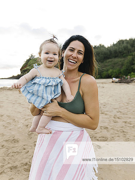 Frau hält ihre kleine Tochter am Strand