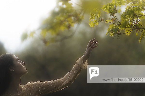 Young woman reaching for branches