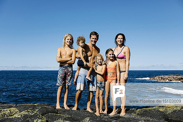 Lächelnde Familie auf Felsen am Meer stehend