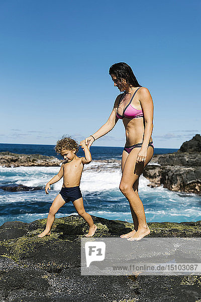 Mutter und Sohn spazieren auf Felsen am Meer