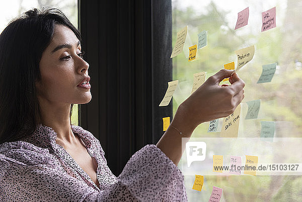 Businesswoman with adhesive notes on window
