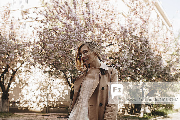 Lächelnde junge Frau bei blühenden Bäumen