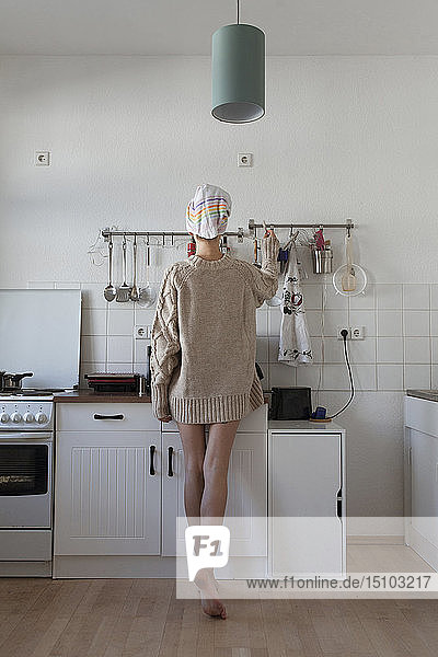 Rear view of young woman in apartment kitchen