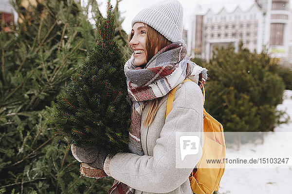 Young woman carrying small Christmas tree