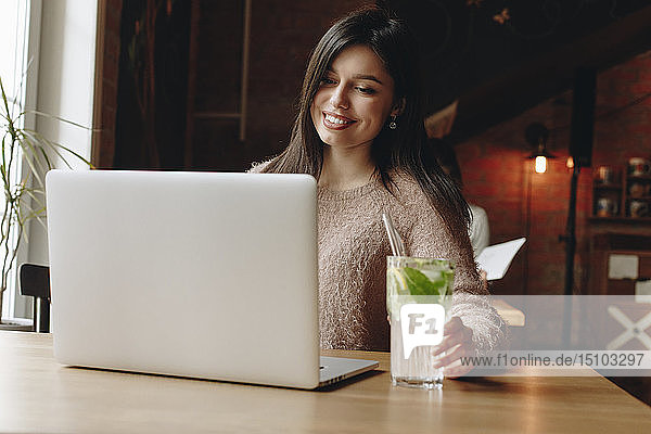 Frau sitzt im Restaurant mit Laptop
