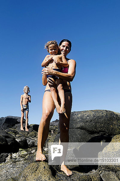 Frau mit ihren Söhnen auf Felsen am Strand