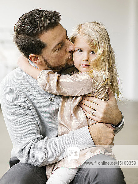 Mid adult man kissing his daughter on the cheek