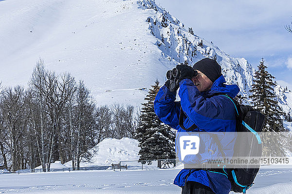 Älterer Mann mit Fernglas an einem schneebedeckten Berg in Sun Valley  Idaho  USA