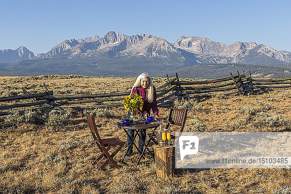 Ältere Frau deckt den Esstisch in einem Feld am Berg in Stanley  Idaho