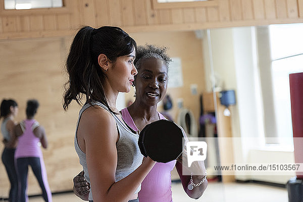 Frau mit Personal Trainer hebt Gewichte im Fitnessstudio