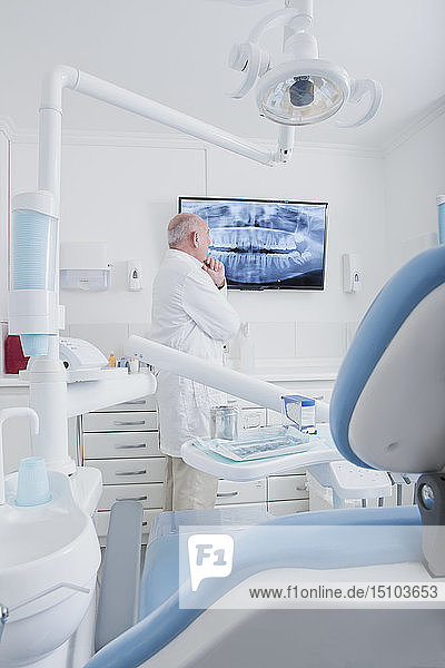 Zahnarzt prüft Röntgenbild auf dem Fernsehbildschirm