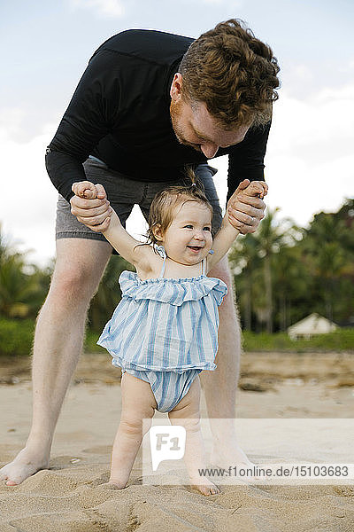 Mann spielt mit seiner kleinen Tochter am Strand