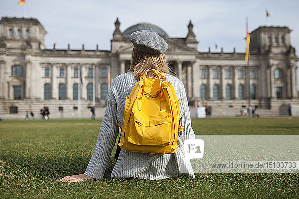 Junge Frau sitzt im Park am Reichstag in Berlin  Deutschland
