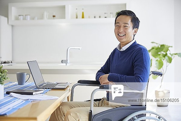 Japanischer junger Mann im Rollstuhl arbeitet von zu Hause aus