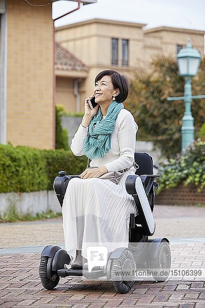 Japanische Seniorin im elektrischen Rollstuhl