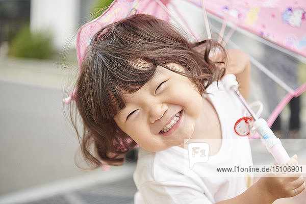 Japanisches Kind draußen mit Regenschirm