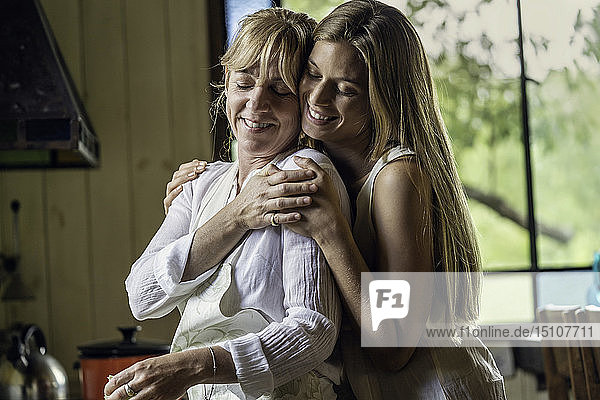 Tochter  die ihre Mutter in der Küche umarmt