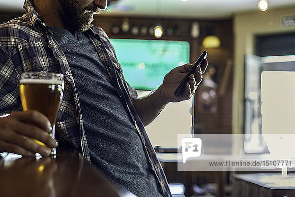 Mann benutzt Smartphone in Bierstube
