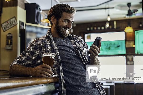 Mann benutzt Smartphone in Bierstube