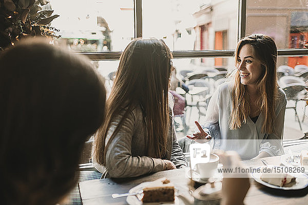 Three happy young women meeting in a cafe
