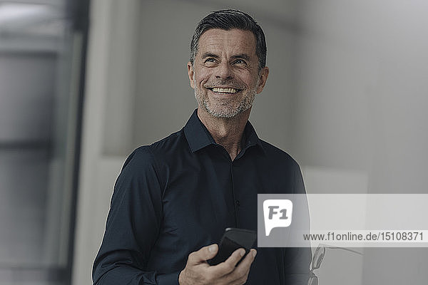 Porträt eines glücklichen reifen Geschäftsmannes mit Handy in der Hand