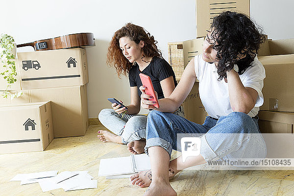 Two friends moving into new home using cell phones