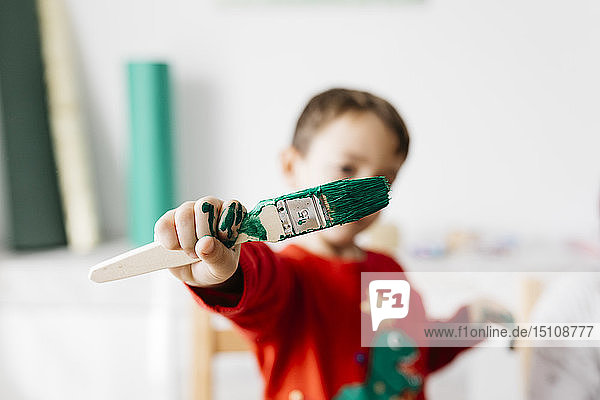 Kind mit einem Pinsel in der Hand beim Basteln zu Hause