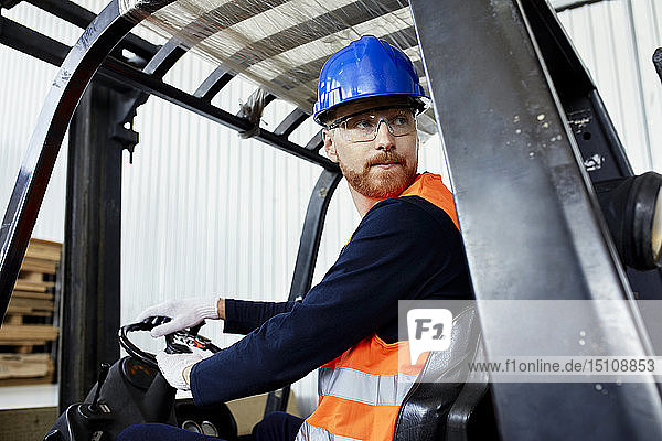 Worker on forklift in factory turning round