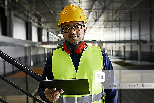 Portrait of worker holding clipboard in factory warehouse