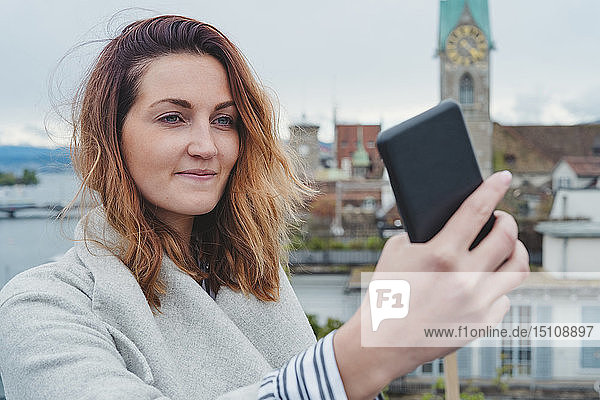 Junge Frau beim Fotografieren mit dem Smartphone in der Stadt  Zürich  Schweiz