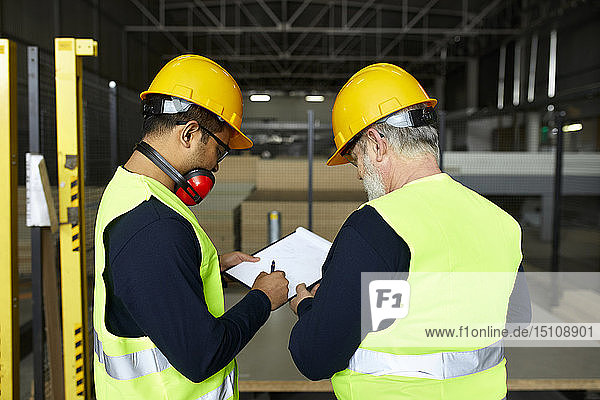 Zwei Männer unterzeichnen Dokument im Fabriklager