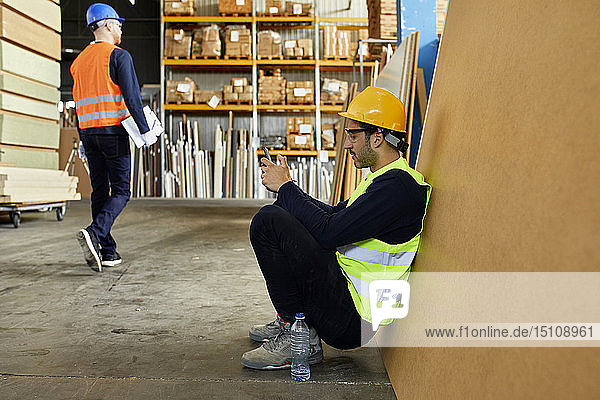 Arbeiter benutzt Mobiltelefon während einer Pause in der Fabrik