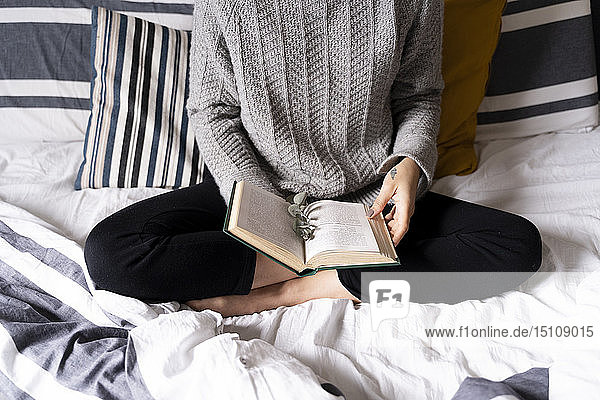 Frau sitzt auf Bett  liest Buch