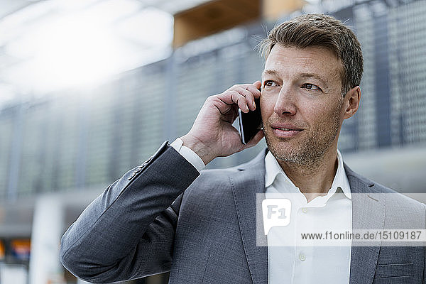 Porträt eines Geschäftsmannes auf dem Handy am Flughafen