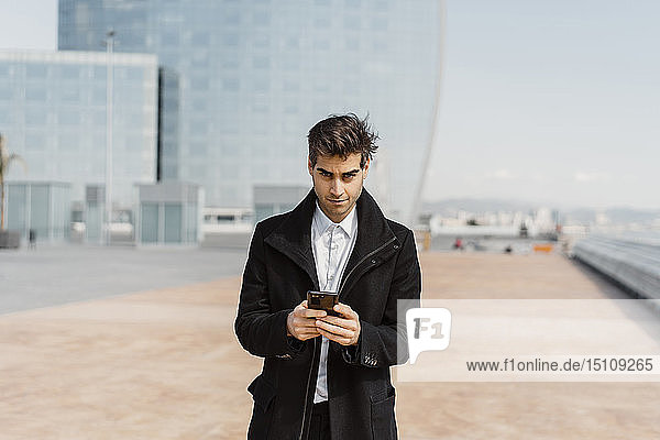 Portrait of businessman holding cell phone in the city