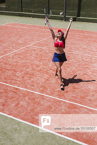 Happy female tennis player cheering on court