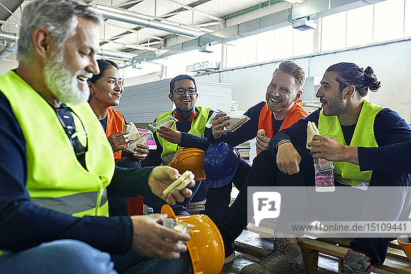 Happy workers in factory having lunch break together