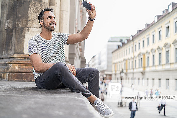 Lächelnder Mann  der sich in der Stadt ein Selfie nimmt