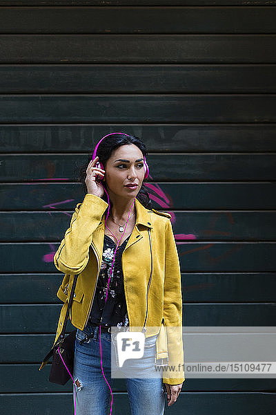 Bildnis einer jungen Frau mit rosa Kopfhörern  die eine gelbe Lederjacke trägt