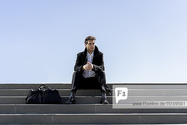 Businessman sitting on stairs having a break