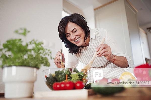 Reife Frau bereitet in ihrer Küche Salat zu