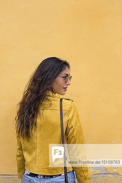 Bildnis einer jungen Frau mit gelber Lederjacke und Sonnenbrille  Rückenansicht