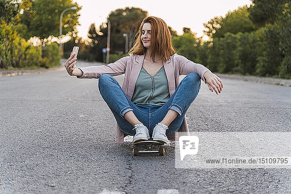 Junge Frau auf dem Skateboard und mit einem Selfie